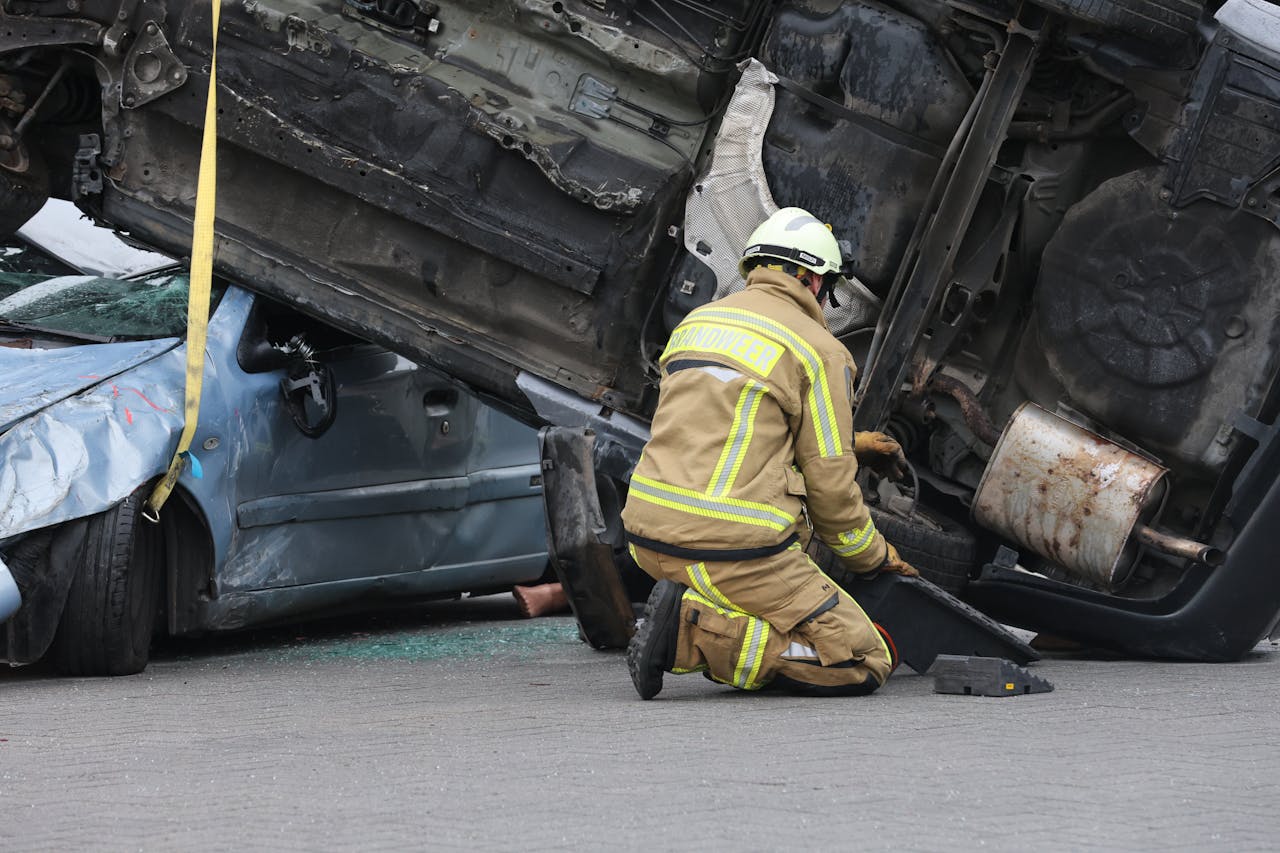 services-01 Firefighter in gear assisting at an overturned car crash scene, ensuring safety during the rescue operation.